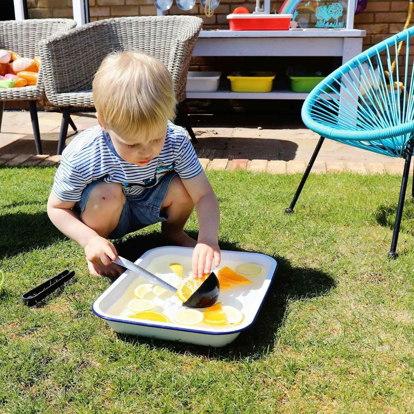 Toddler playing with a bowl of lemons in water and a ladle for sensory play