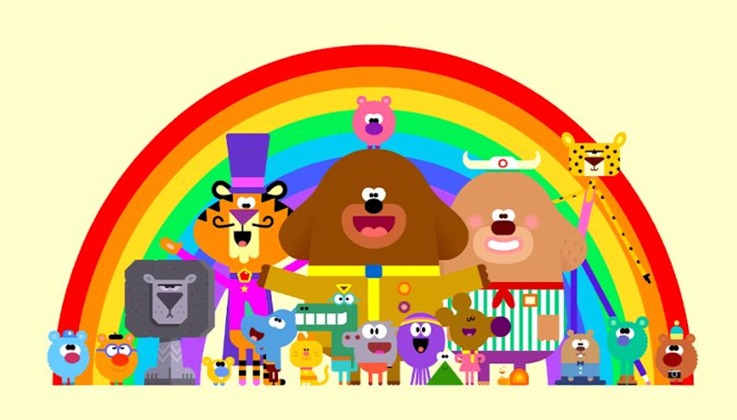 Duggee and the cast of Hey Duggee in front of a rainbow