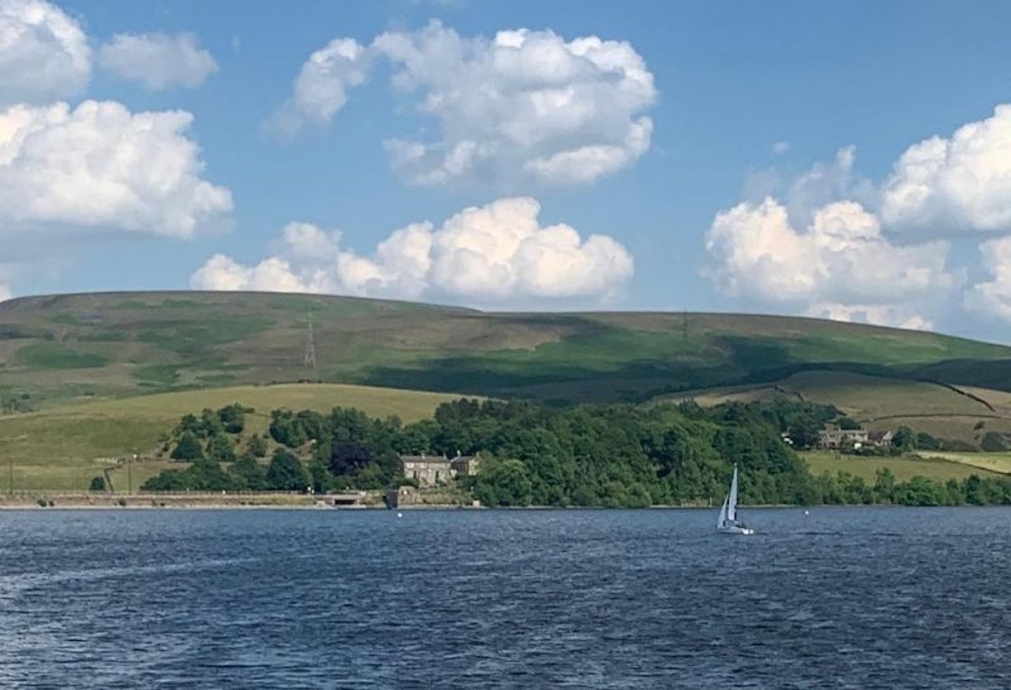 Virginia Water in front of hills with a boat on the water