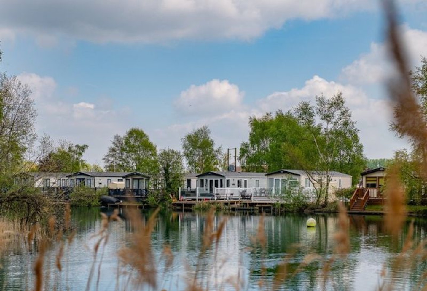 Holiday lodges set around a lake with trees in the background