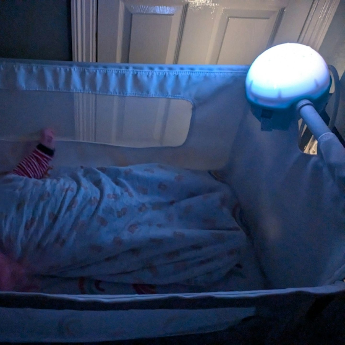 baby in the cot with the Chicco Next2 Stars Night Light Projector attached