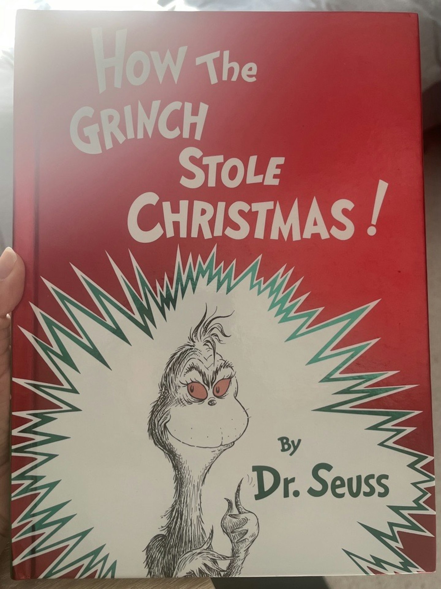 A copy of How the Grinch Stole Christmas with a red cover and The Grinch