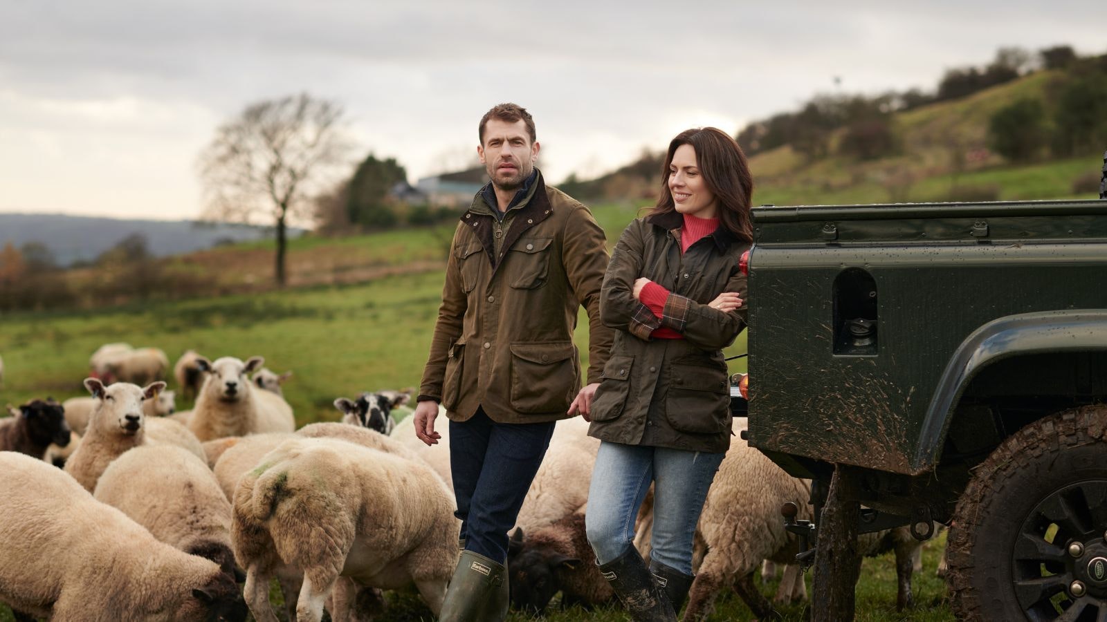 Liz and Kelvin Fletcher surrounded by sheep on their farm.