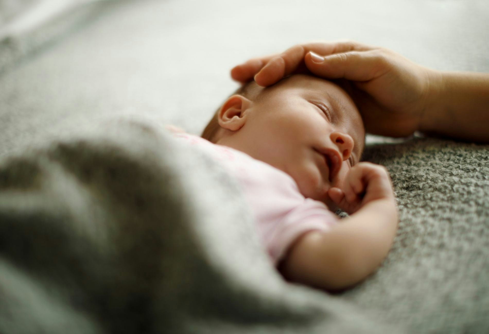 A sleeping newborn baby with a parent