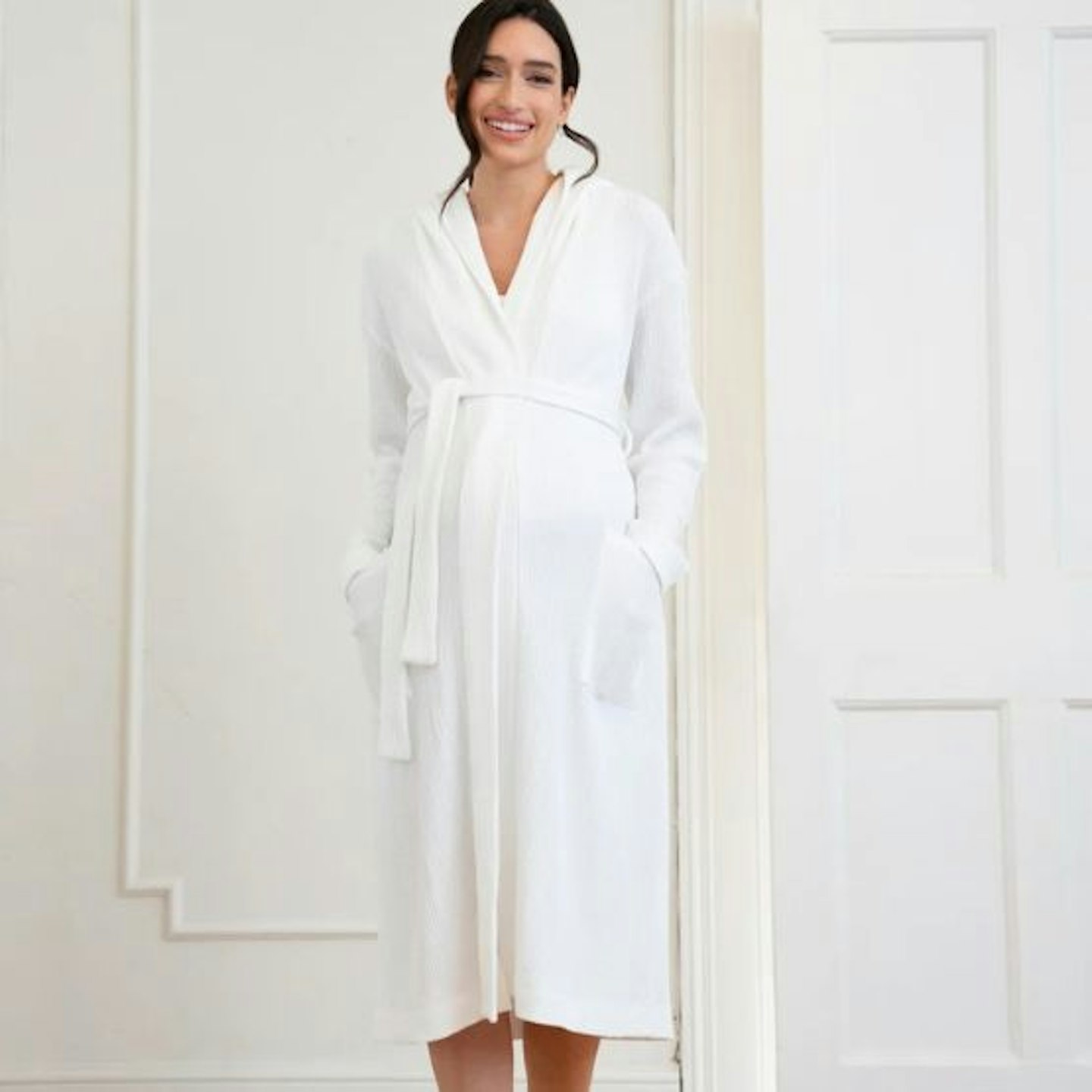 A woman in a white dressing gown standing in front of wardrobe doors