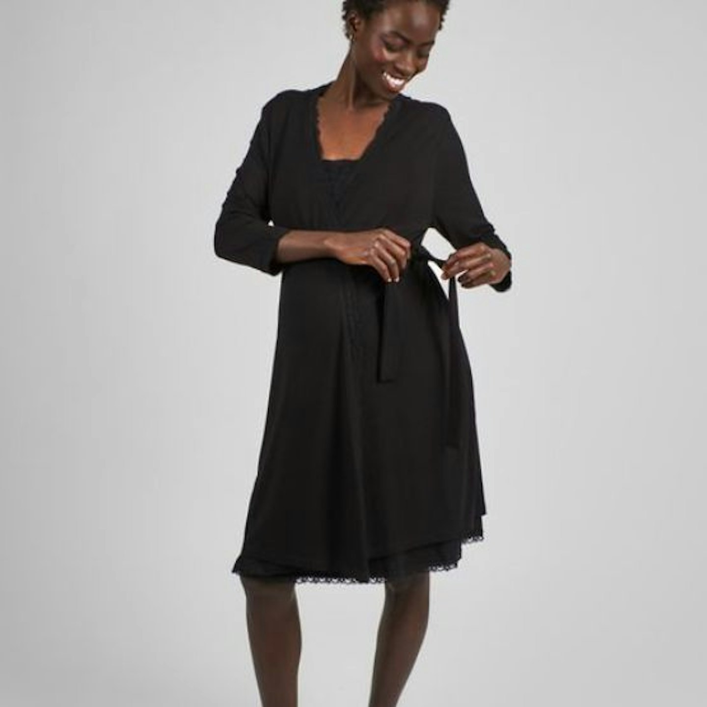 A black woman wearing a black maternity robe with lace trim