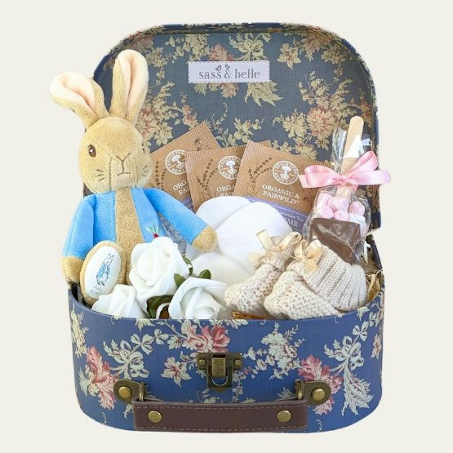 A flowery trunk with a Peter rabbit soft toy, tea bags, booties and mittens