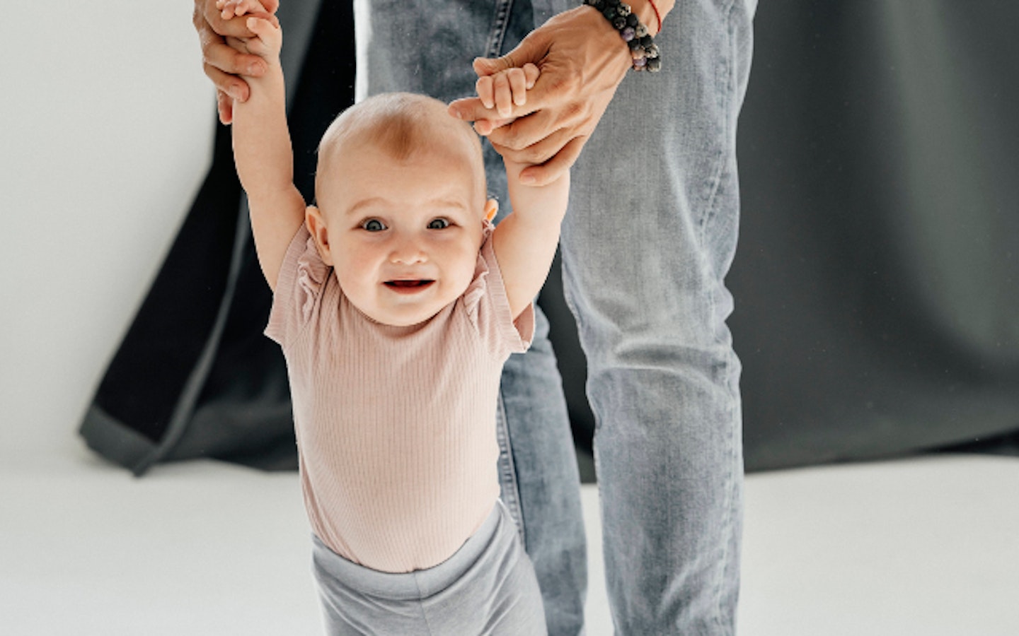 baby trying to walk being held by father