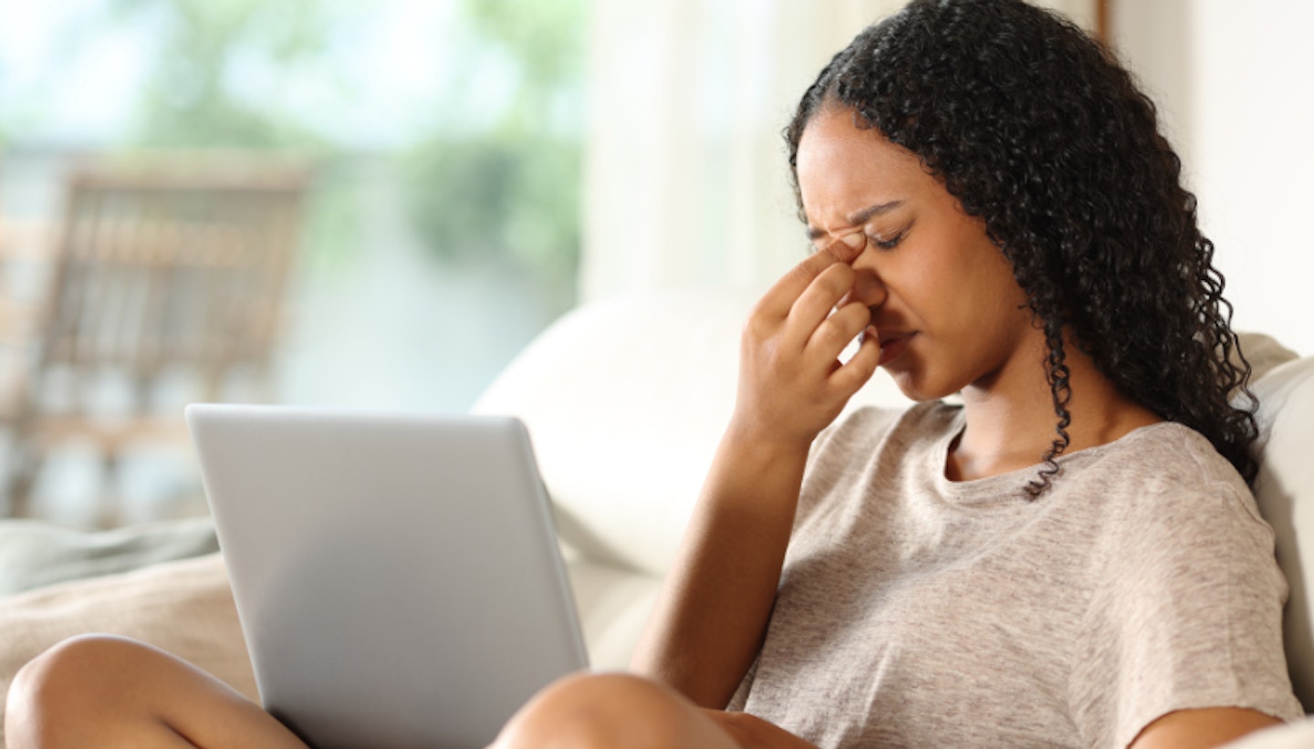 woman sitting down in front of laptop looking stressed