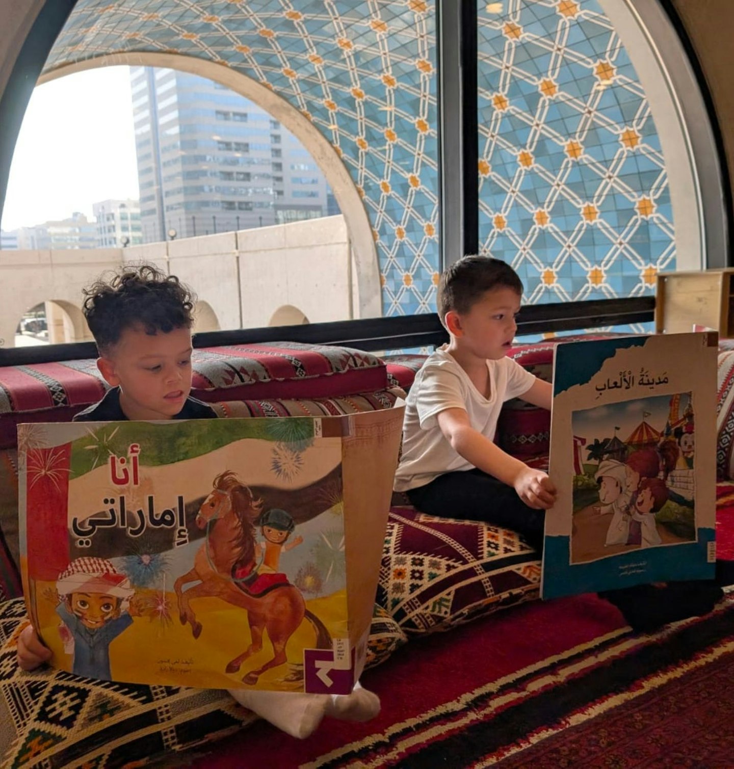 Two little boys looking at arabic books at Abu Dhabi Children's Library.