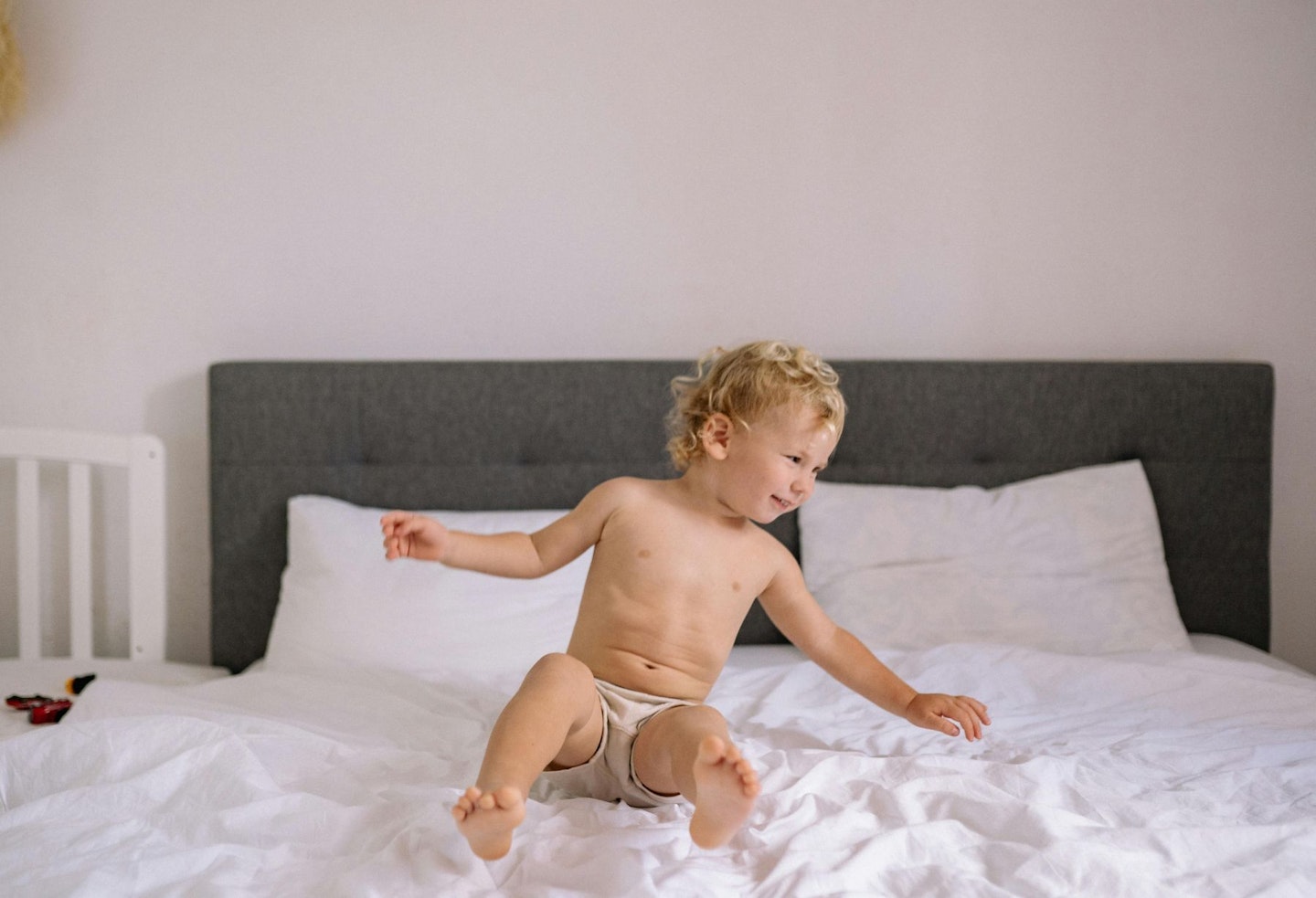 Little Boy Sitting on a Bed in a Diaper and Smiling