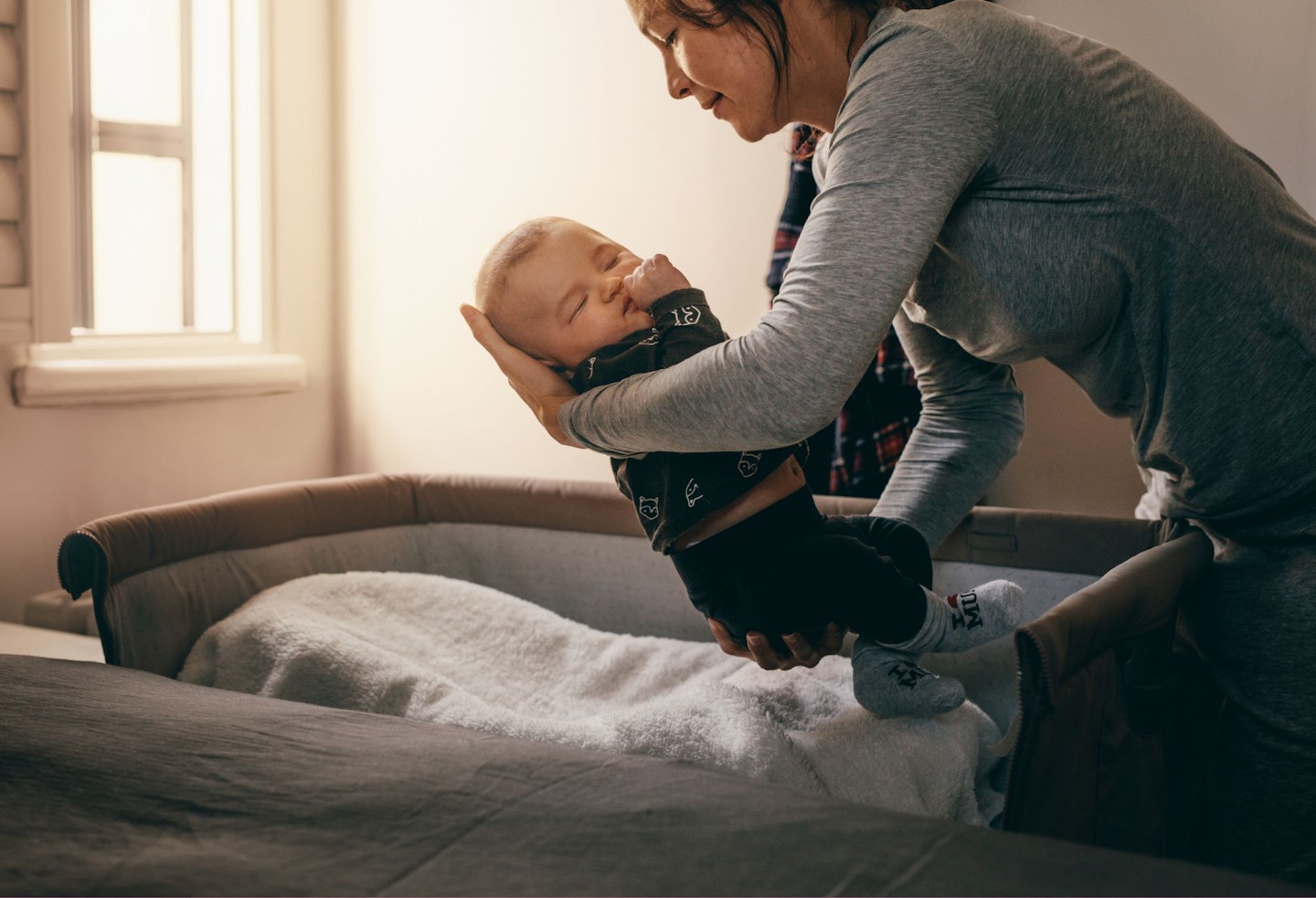 Mother Putting Her Baby to Sleep on a Bedside Baby Crib