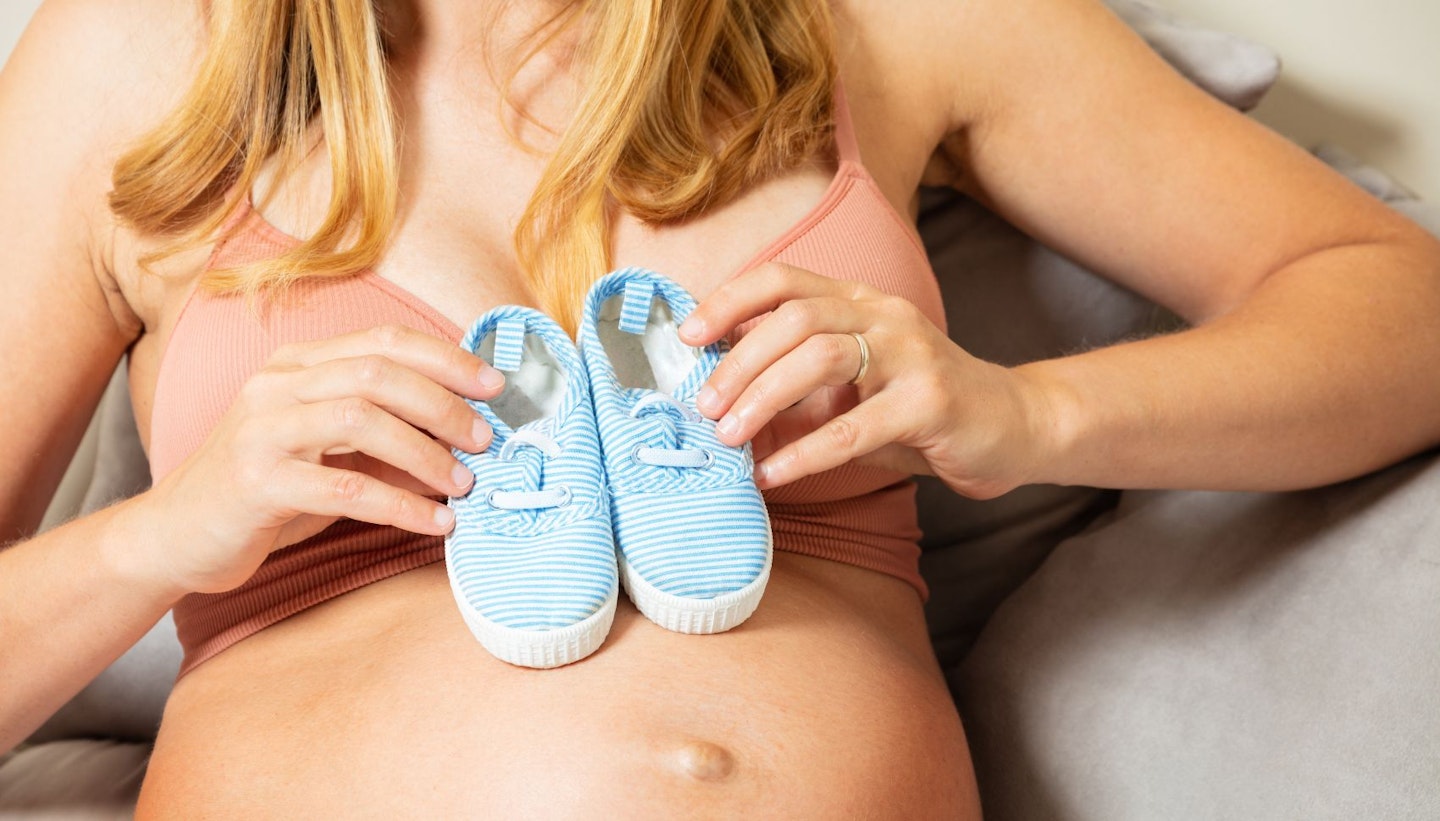 Pregnant woman hold small tiny newborn boots