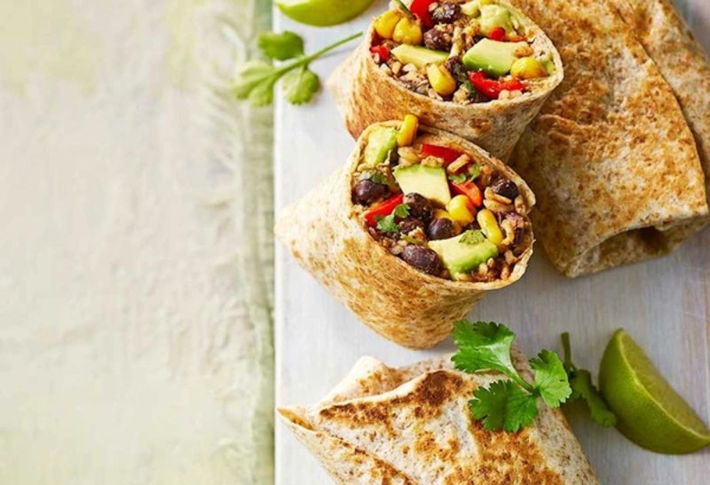 Two burritos cut in half to show the filling of sweetcorn, chicken and avocado