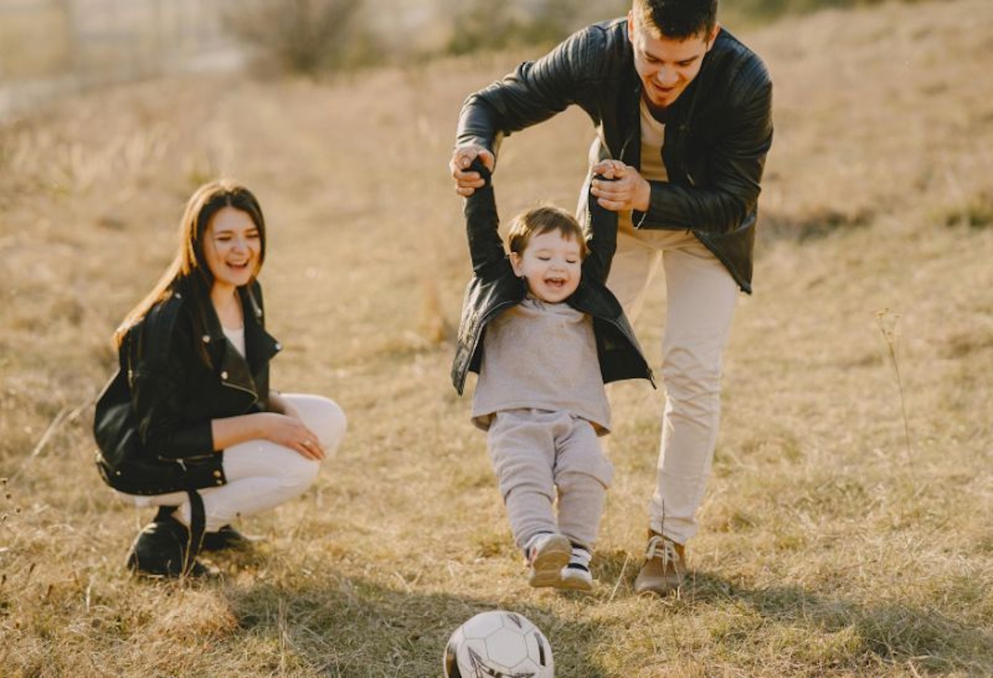 Two adoptive parents with their child on a park