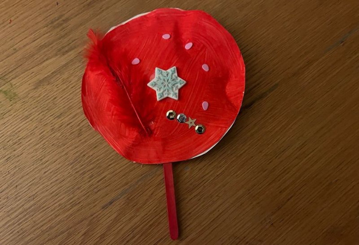 A red Chinese shaker decorated with stars and a red feather