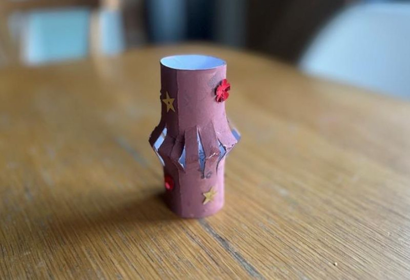 A homemade Chinese lantern made from a toilet roll and painted in purple with sequins