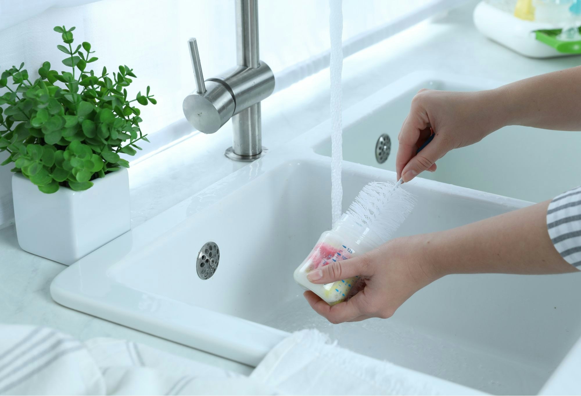 Woman Washing Baby Bottle in Kitchen, Closeup
