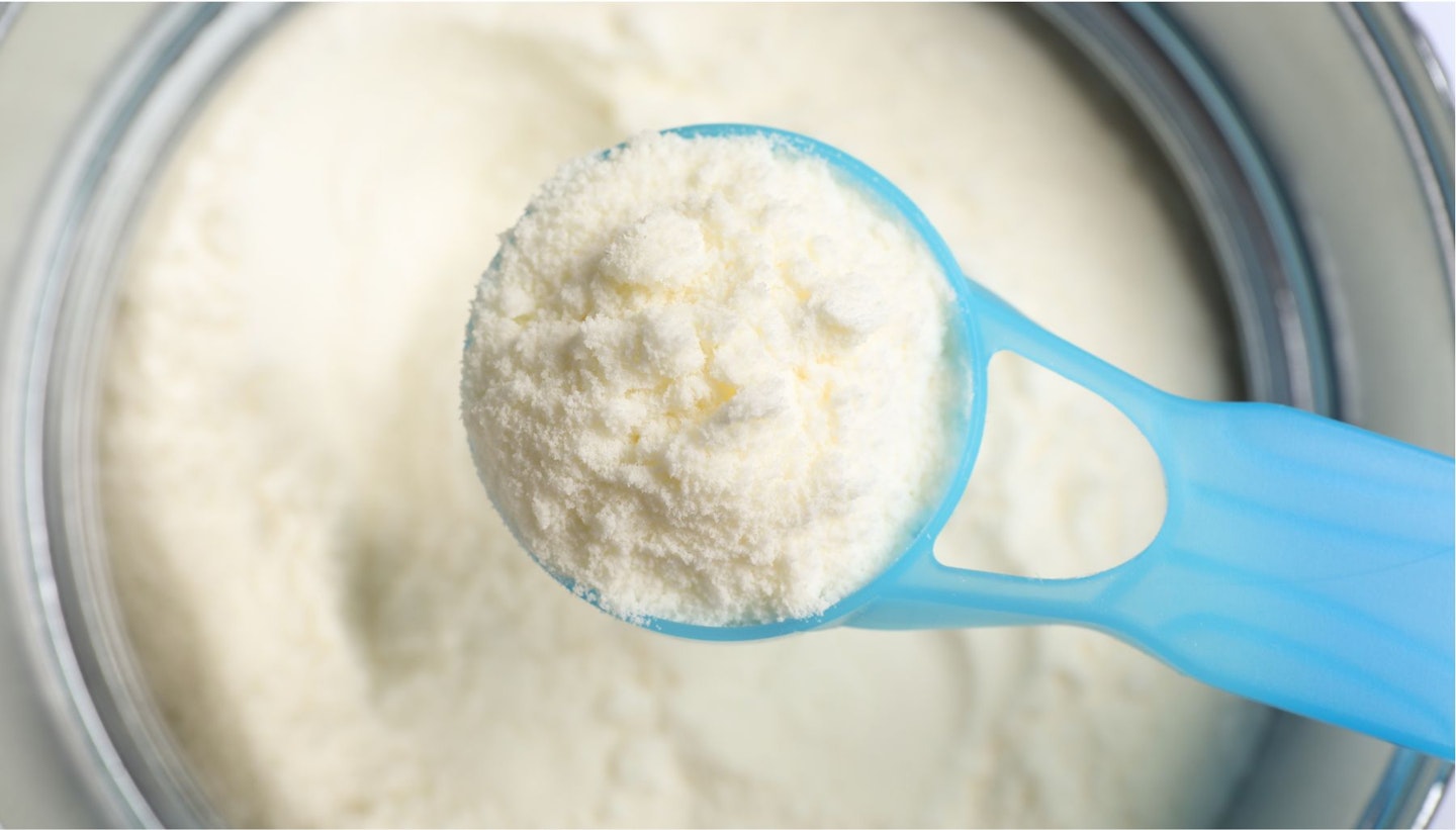 Scoop of Powdered Infant Formula over Can, Top View. Baby Milk