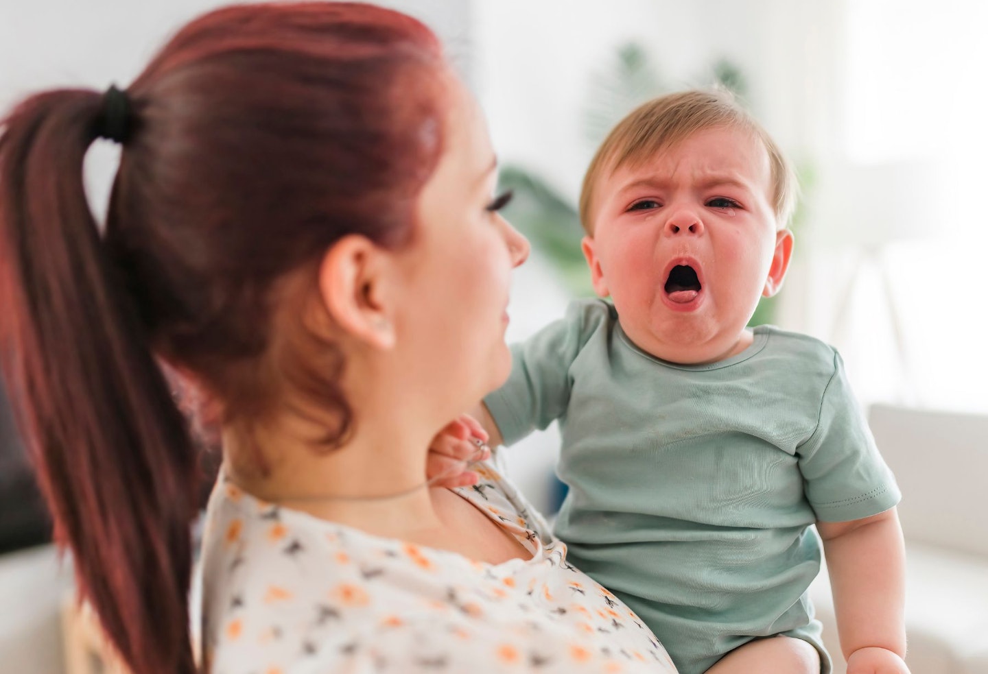 mother holding child baby on the living room. The baby is sick having some cough