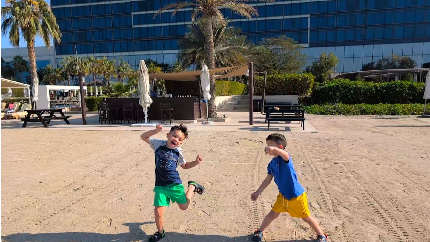 Two little boys playing on the beach happily at the Fairmont Bab Al Bahr hotel.