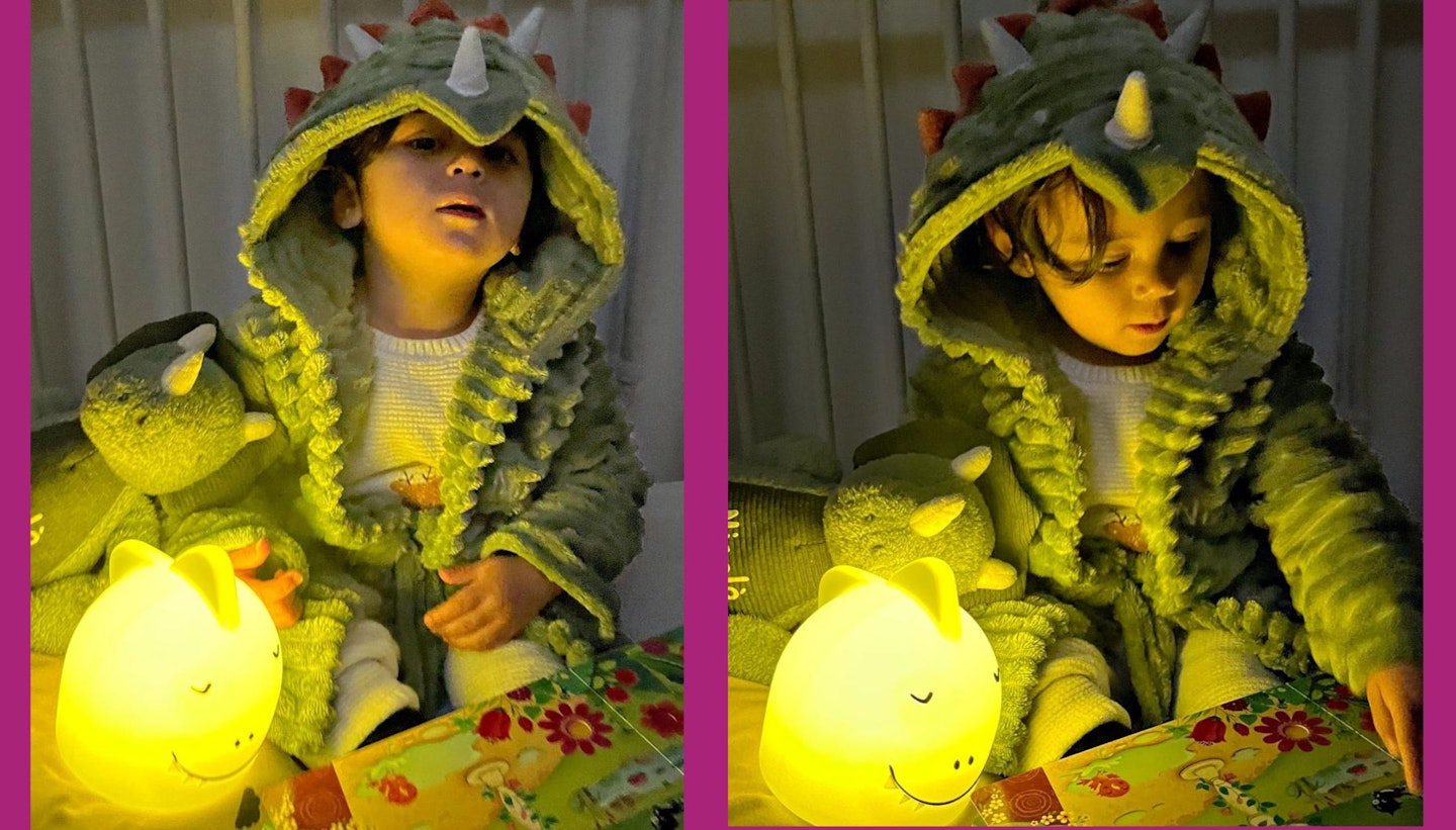 Toddler playing with a glowing dinosaur nightlight at bedtime.