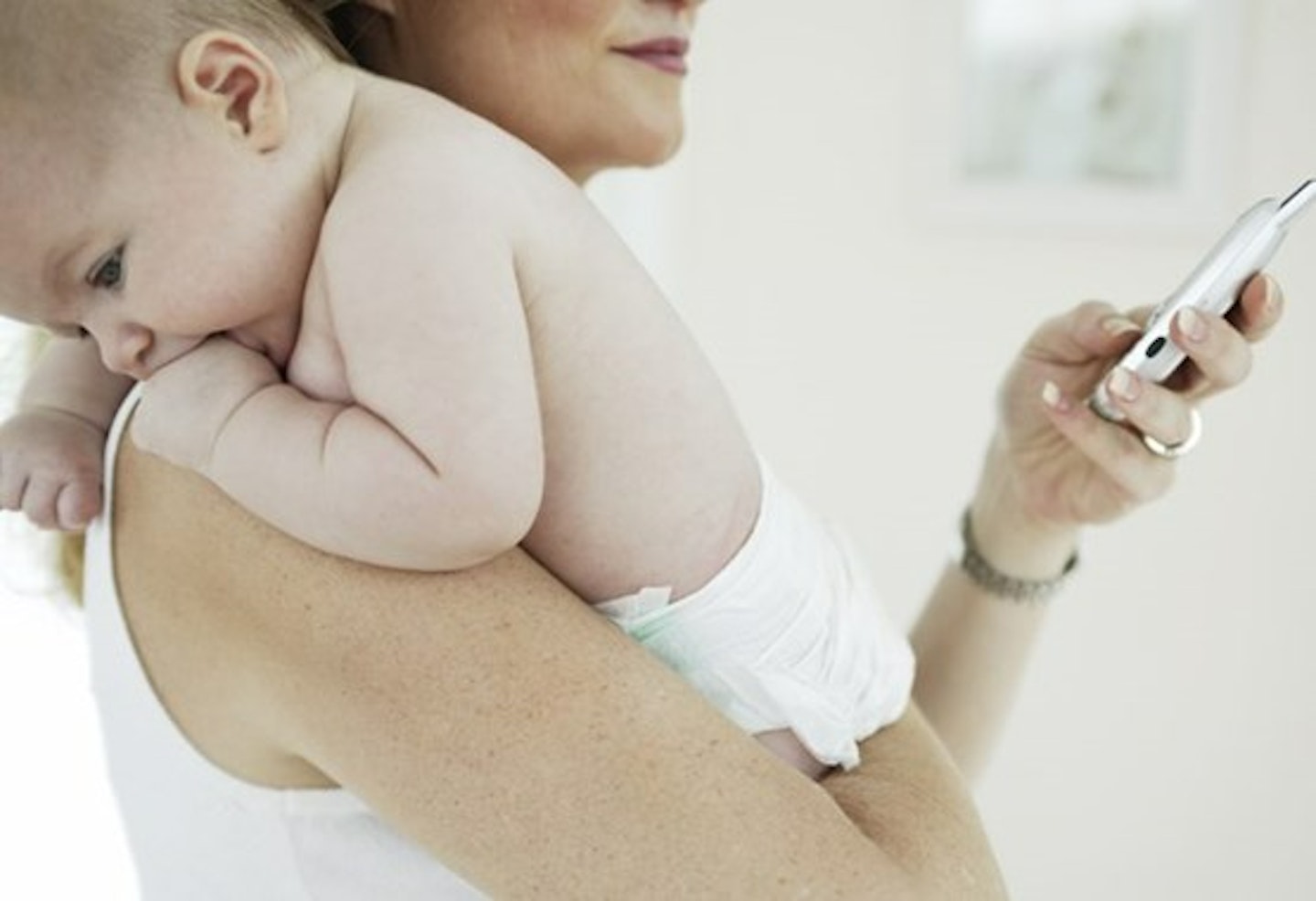 Mum holding baby in arms whilst on her phone