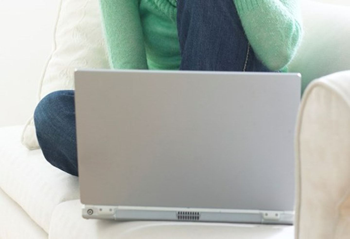 Woman typing on laptop on sofa