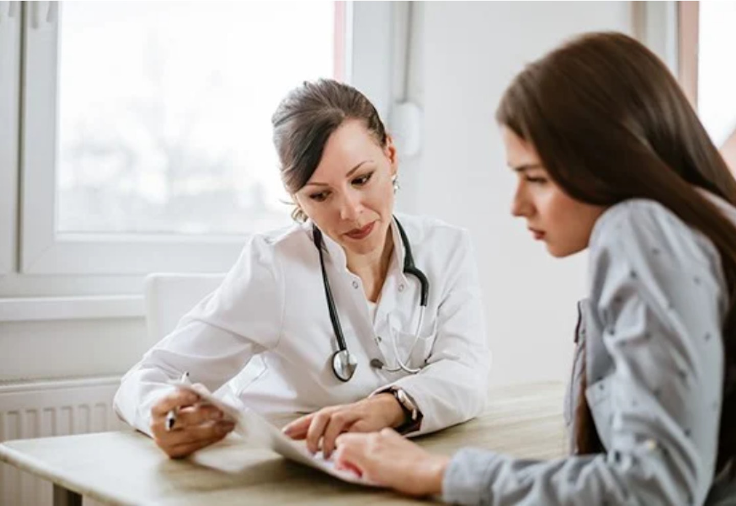 A woman looking at a document with a doctor