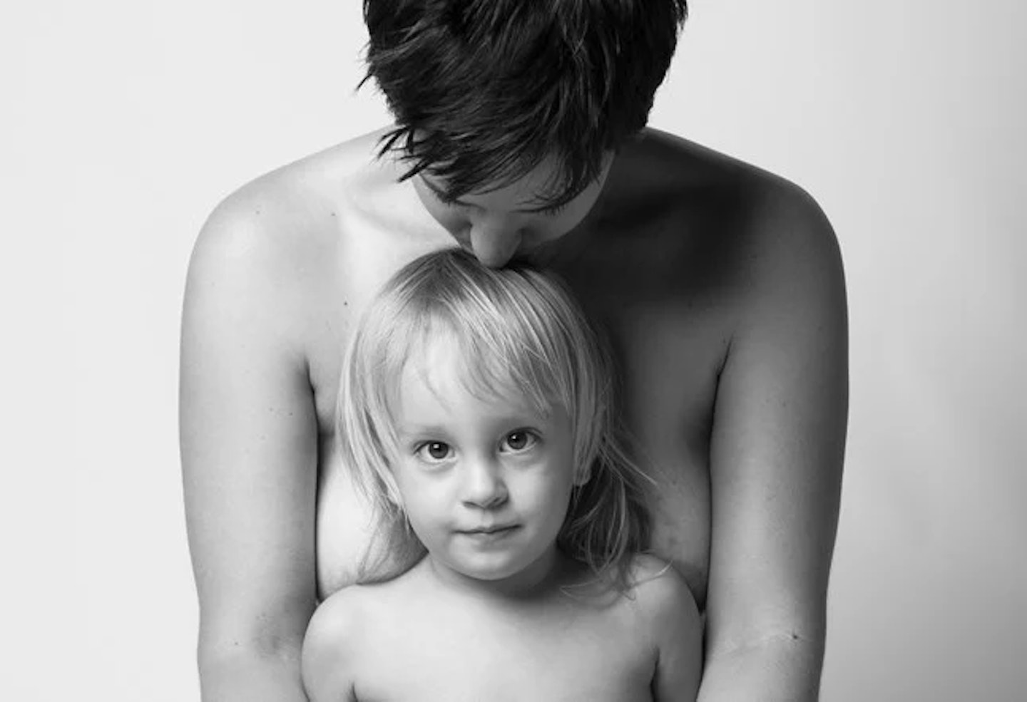 topless mother kissing her child on the head