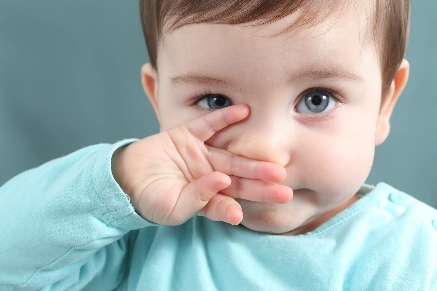 Toddler wipes face looking at camera