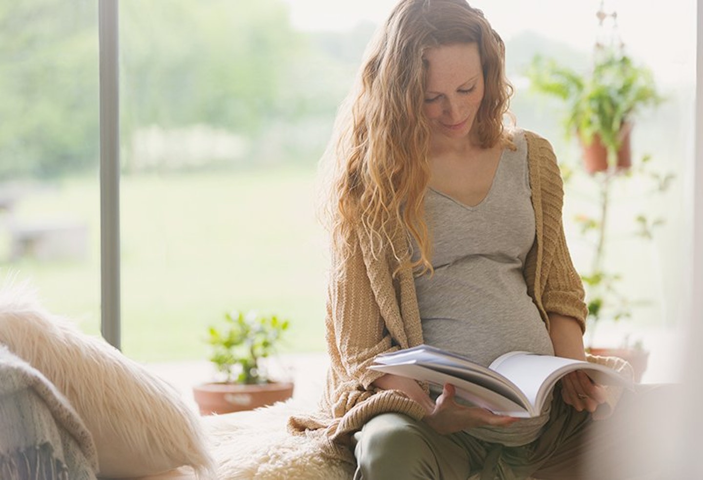 pregnant woman reading with a window behind