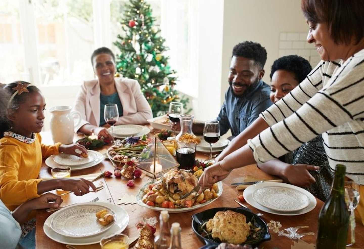 Woman cutting meat for family and friends on dining table at home during Christmas festival