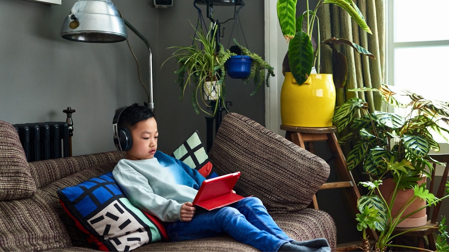 Young Chinese boy wearing headphones watching movie on tablet