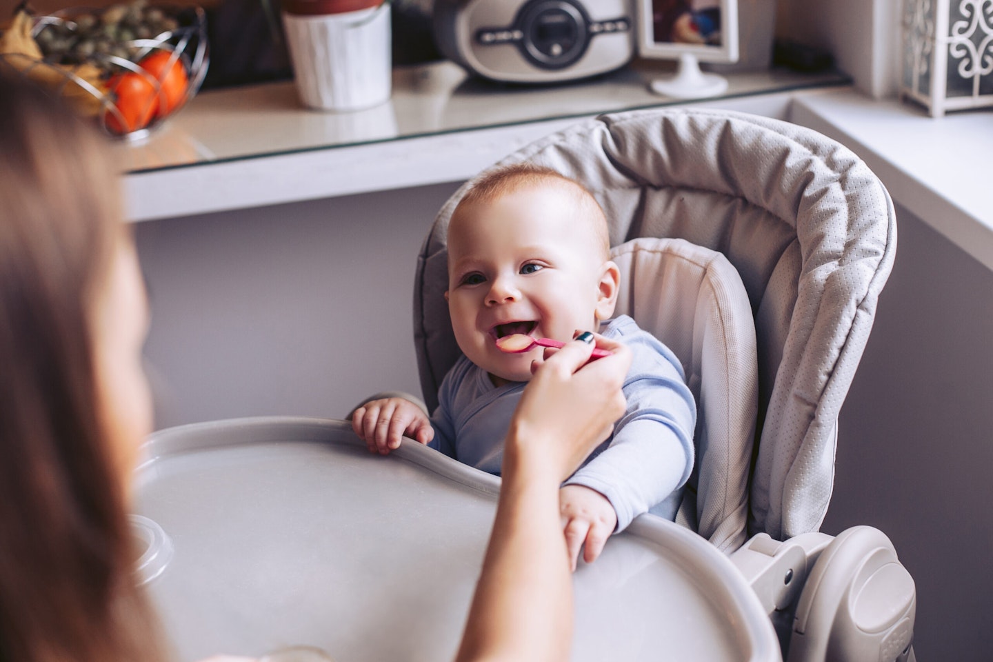 baby in a highchair being fed by mum