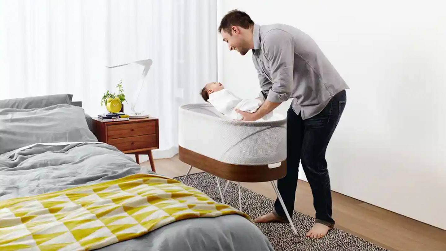 dad putting baby down into baby rocking bed