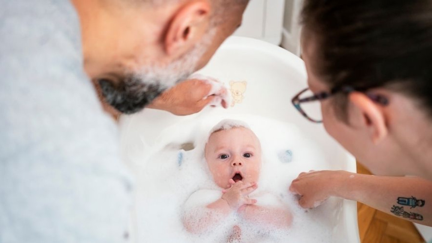 Parents looking down on their baby in a baby bath