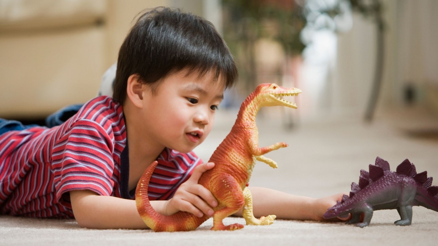 Young boy playing with dinosaur toys - stock photo