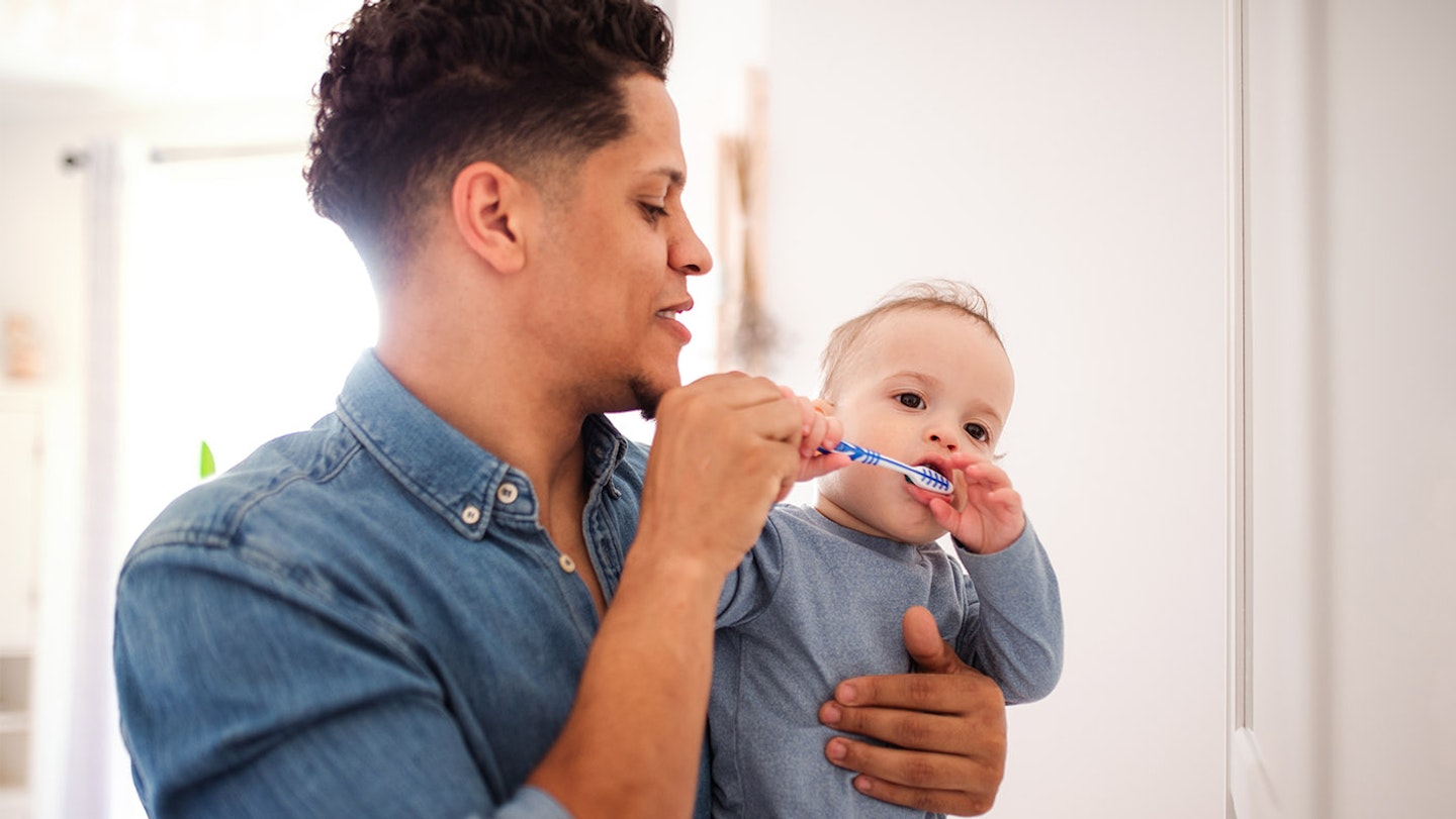 parent brushing baby's teeth