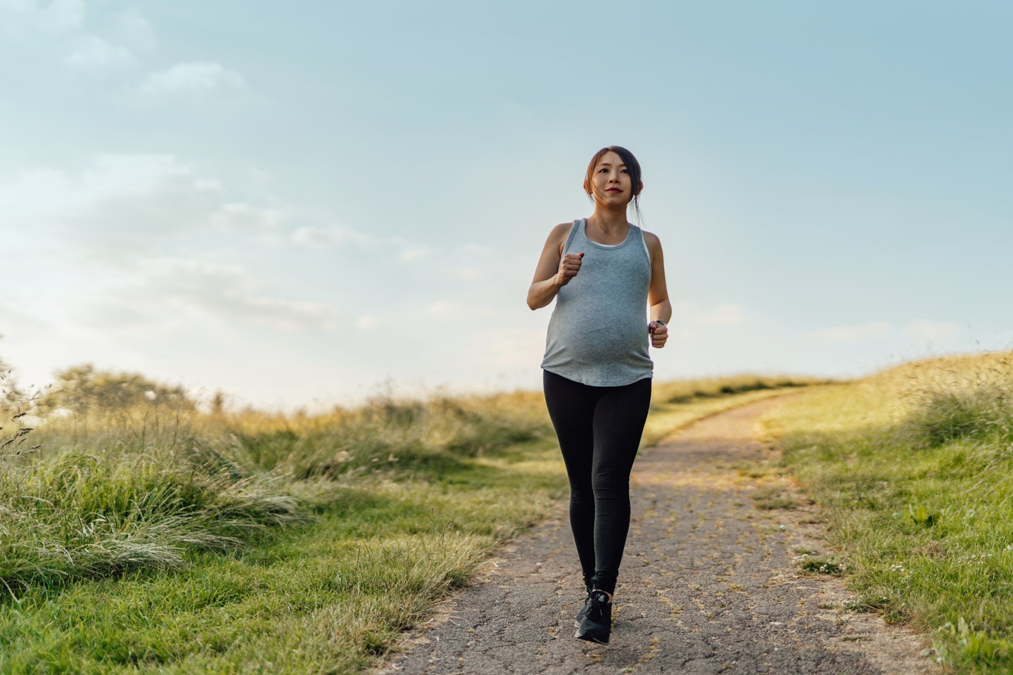 pregnant woman running along a trail outside