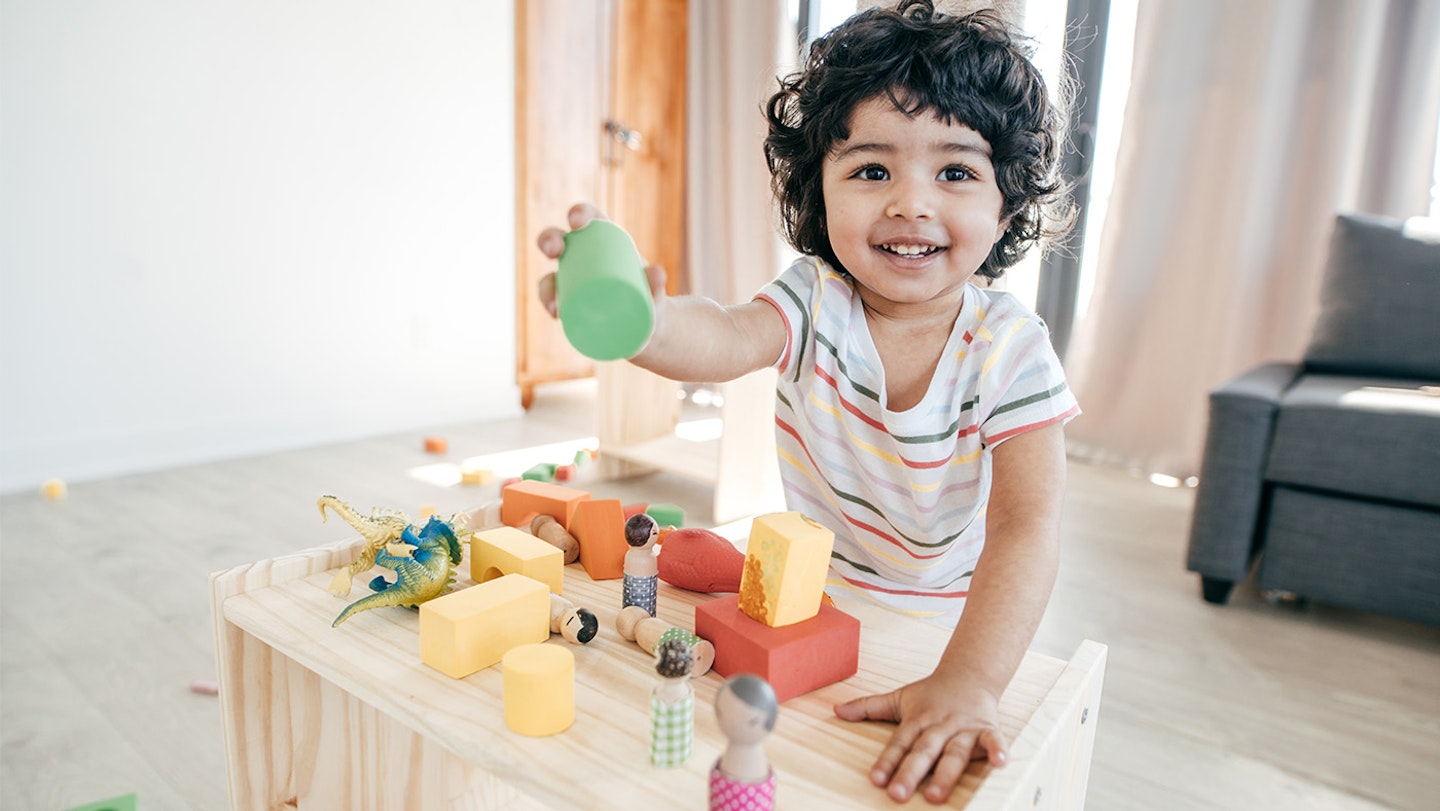 baby holding wooden toys