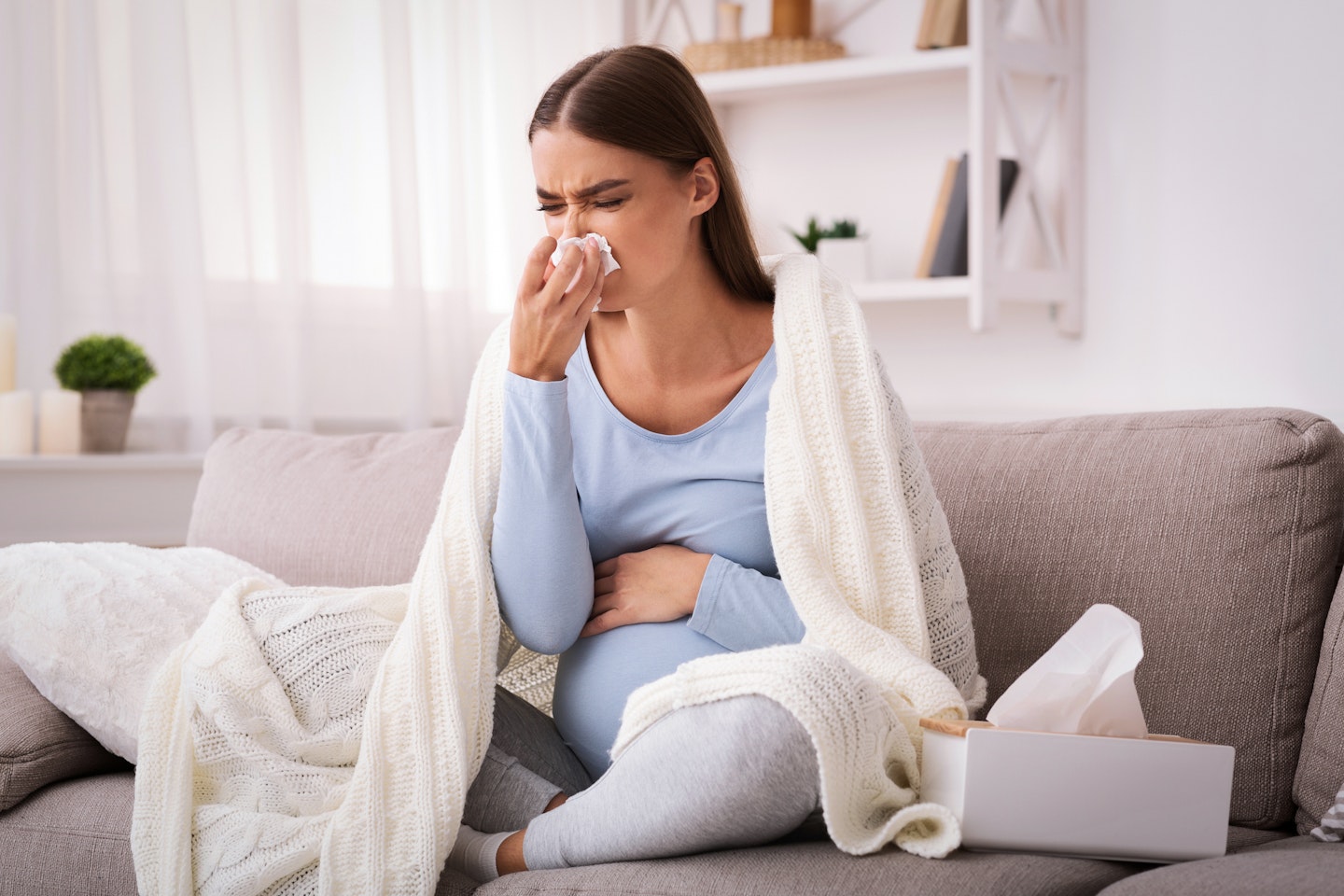 pregnant woman blowing nose suffering from hay fever