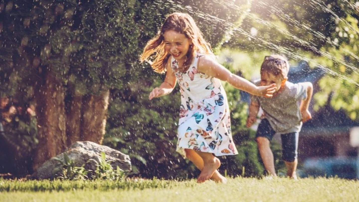 Children playing underneath a sprinklers for kids