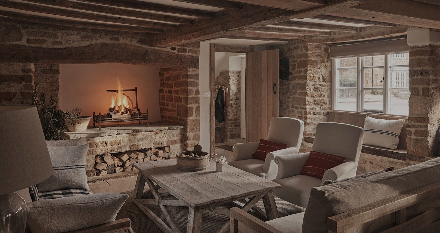 The lounge at Wild Rabbit in The Cotswolds, with a fire and comfy armchairs
