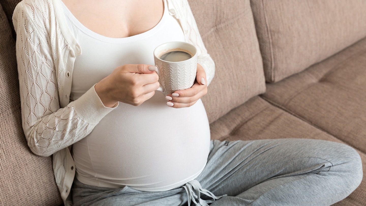 pregnant woman holding a coffee