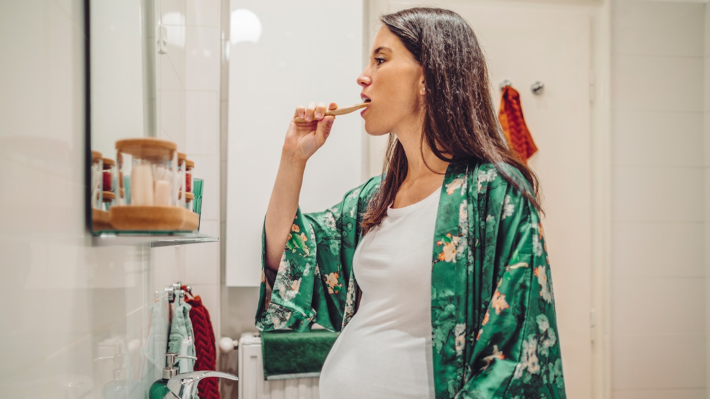 pregnant woman brushing her teeth