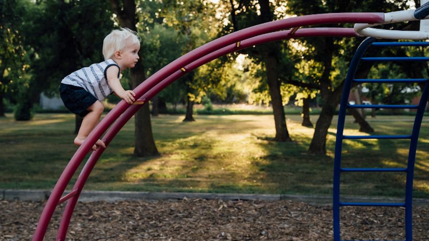 A toddler climbing a climbing frame