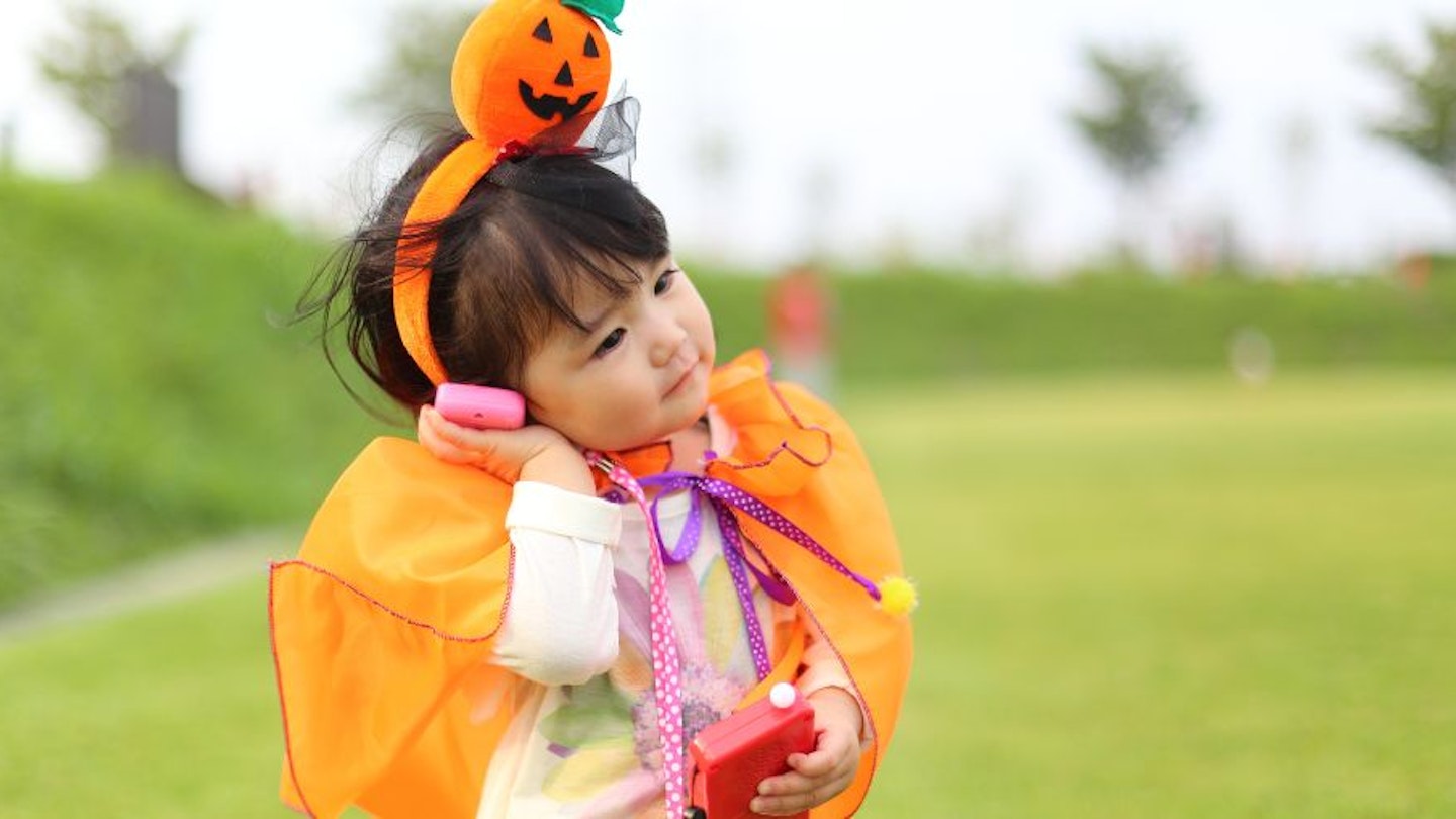 A little girl dressed for Halloween while playing with toys