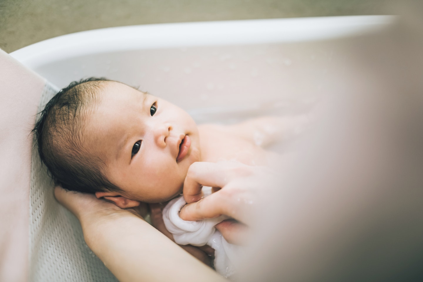 Mum washing newborn in bath