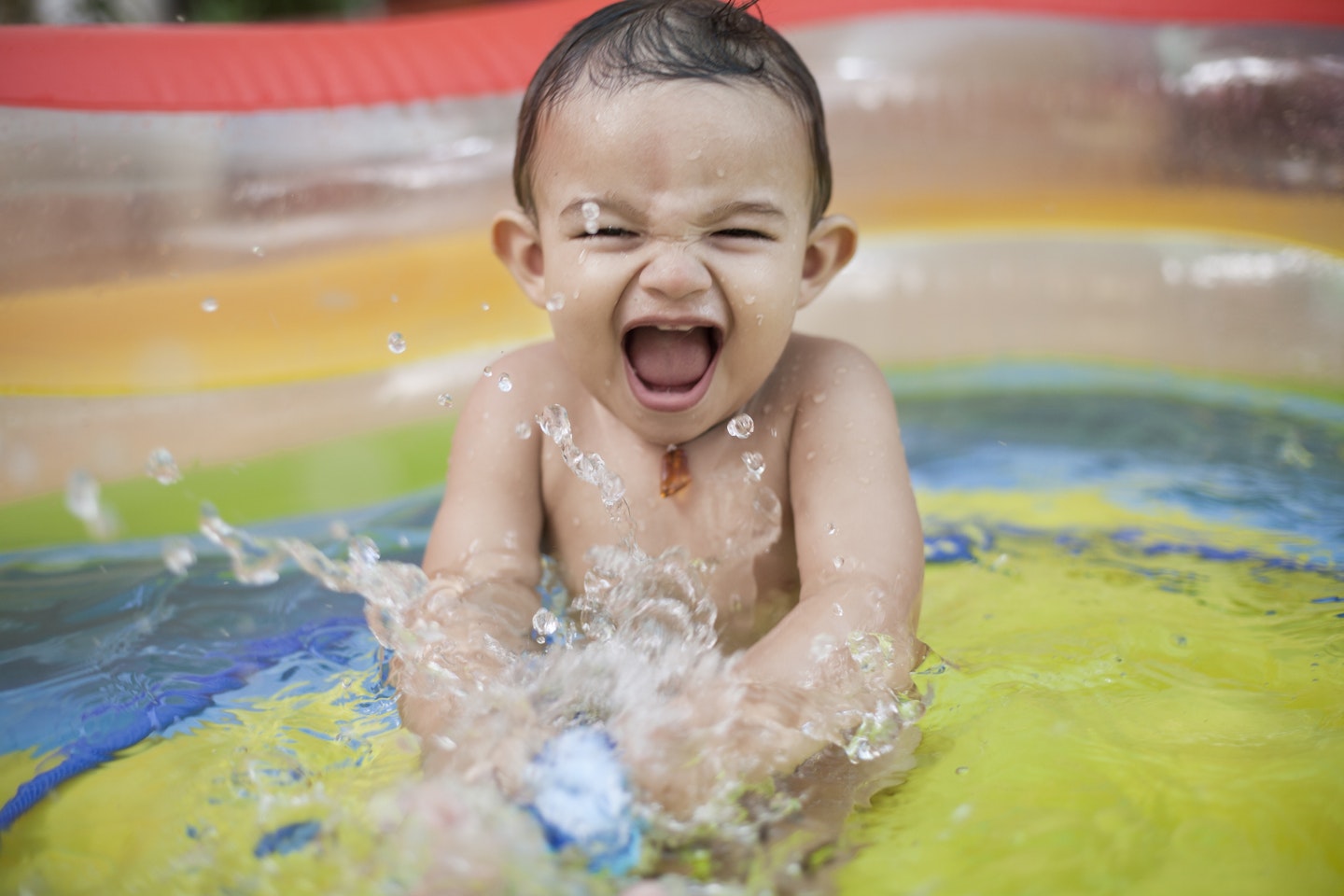 little boy splashing in paddling pool